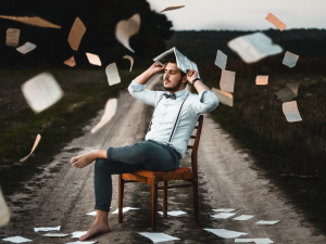 Man sitting at a chair with book pages raining down