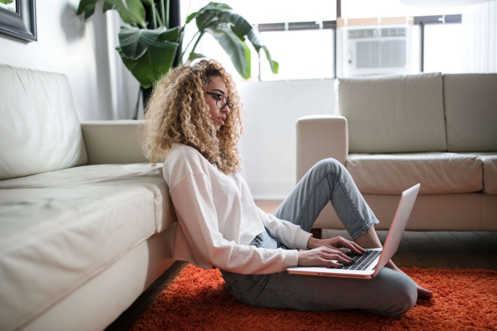 woman working remotely at home on laptop sitting on the floor